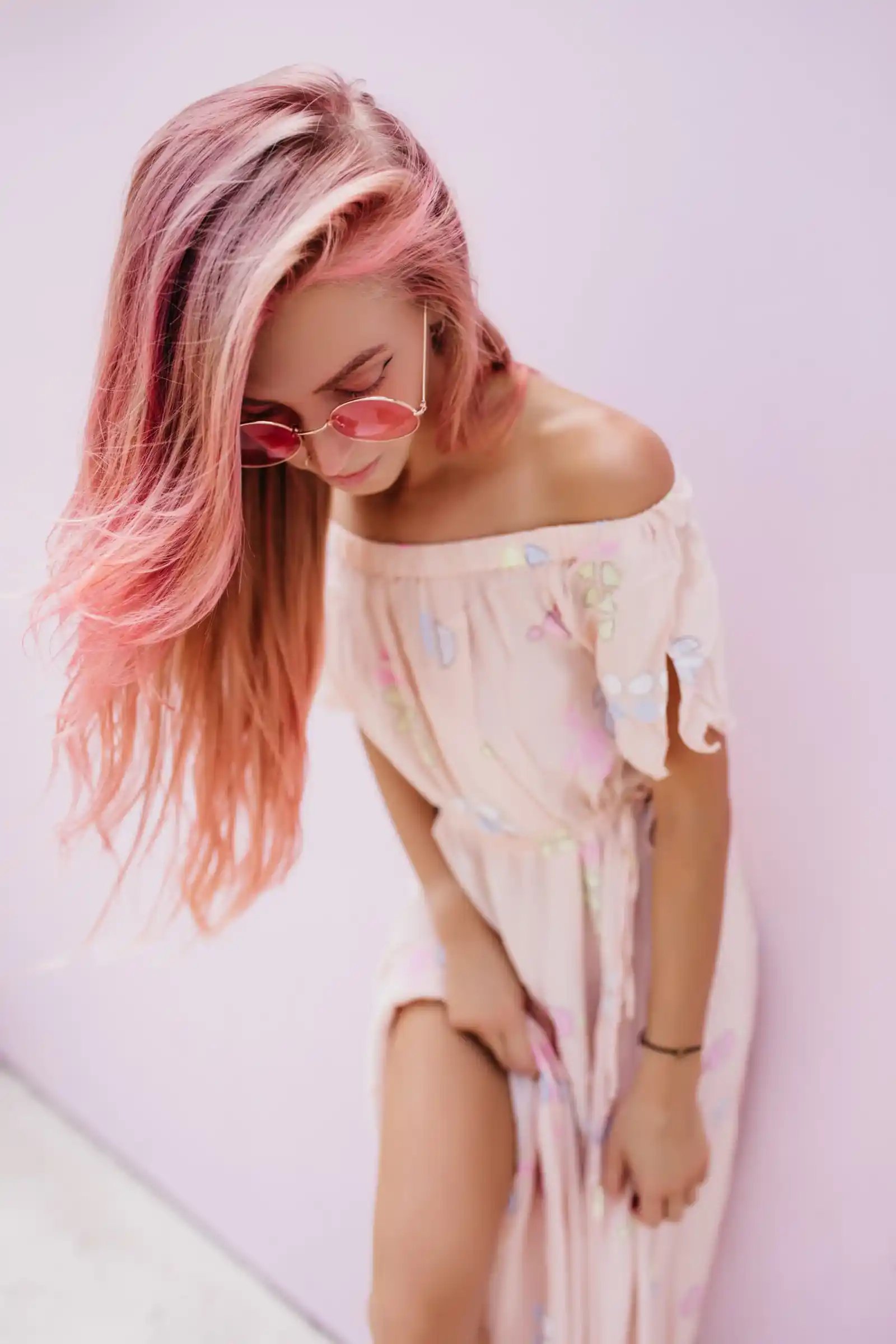 Persona con cabello rosa y vestido blanco, mostrando estilo y moda vanguardista.