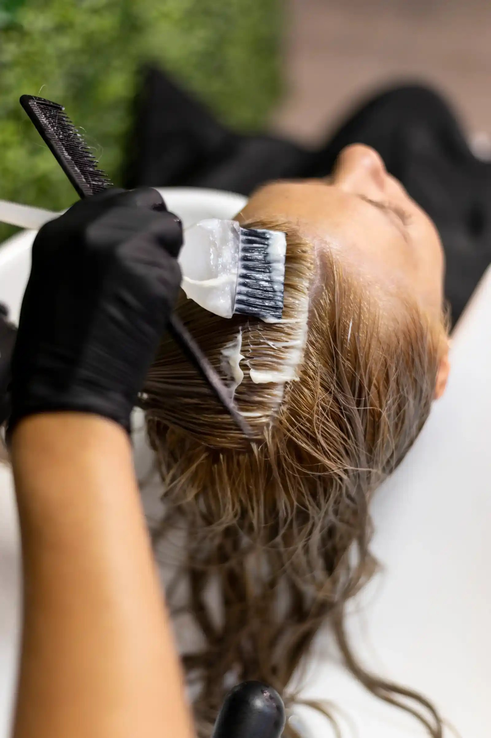 Aplicación de tinte en el cabello, representando servicios personalizados de coloración.