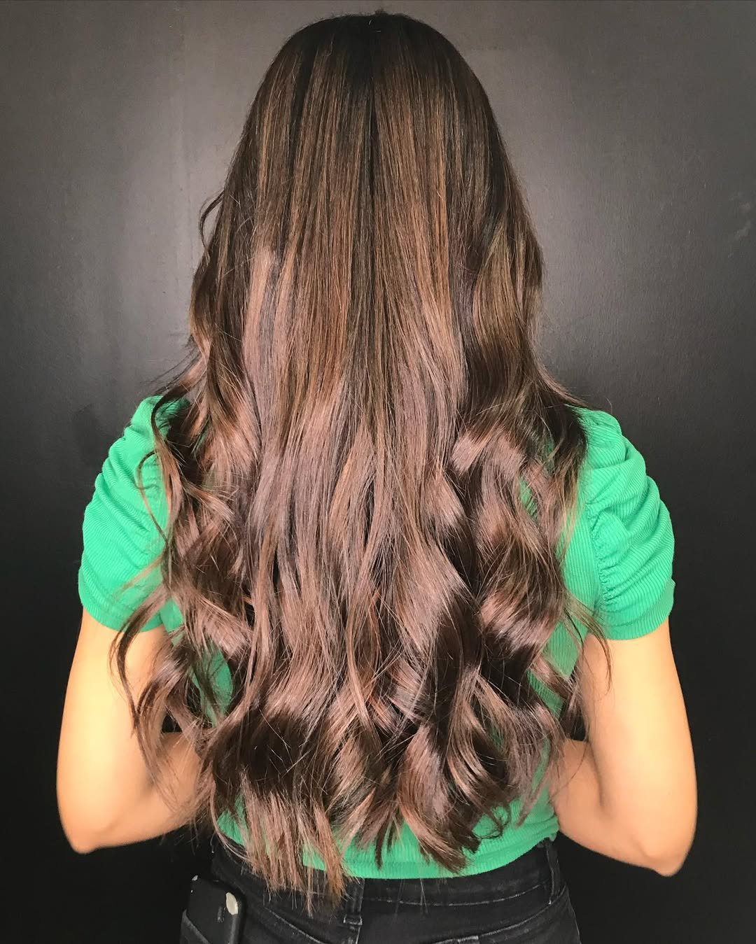 Mujer radiante mostrando su cabello recién peinado con elegancia.