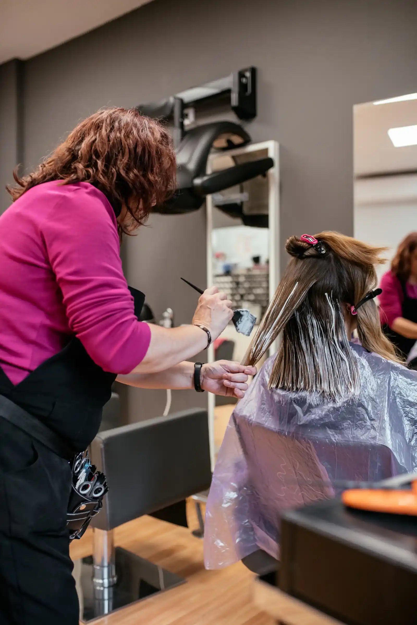 Aplicación de tinte en el cabello, ilustrando servicios de coloración en la peluquería.