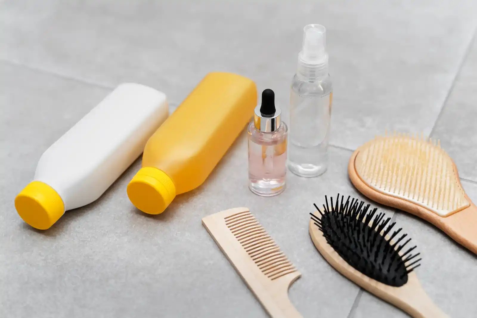 Productos para el cuidado del cabello como botellas, cepillos y peine, destacando herramientas de alta calidad.