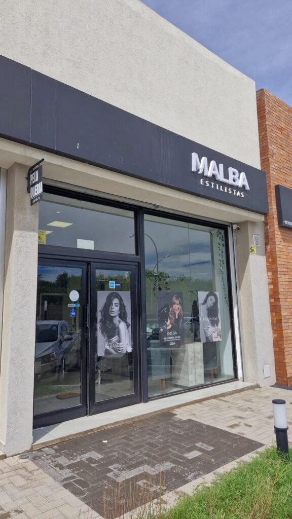 Exterior del salón "Malba Estilistas" con posters de modelos, destacando la estética y profesionalismo del lugar.